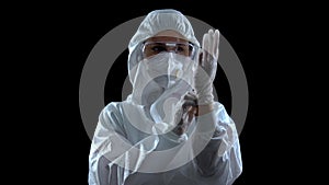 Person in protective suit wearing rubber gloves against dark background, toxins photo