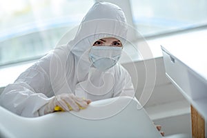 Person in protective workwear making home disinfection