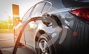 Person pumping gas. Fuel petrol for car at gasoline oil station nozzle in tank. Hand and black refueling gun close-up