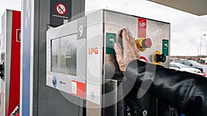 Person pumping gas. Fuel petrol for car at gasoline oil station nozzle in tank. Hand and black refueling gun close-up.