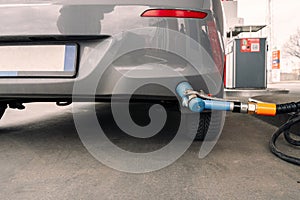 Person pumping gas. Fuel petrol for car at gasoline oil station nozzle in tank. Hand and black refueling gun close-up.