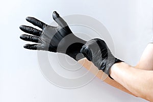 Person put on black latex gloves on white background