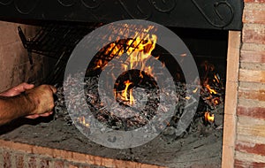 A person puts a grill in the fireplace next to the fire to heat it