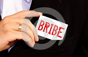 a person puts in his pocket a card labeled BRIBE