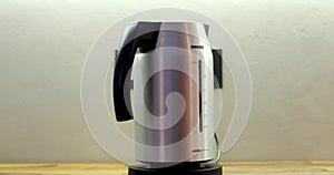 Person putting electric kettle on black stand