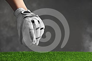 Person putting golf ball on green grass against grey background, space for text