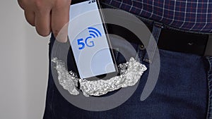 Person putting a smartphone in his pocket covered with foil