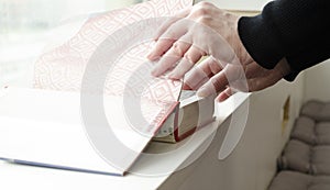 A person reading books near the window. Hands turns over book page