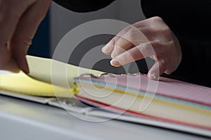 A person reading books near the window. Hands turns over book page