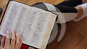 Person reading Holy Bible Book at home, female hands turning pages and studying old testament Scriptures