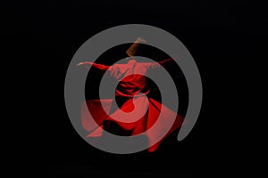 Person in a red dervish costume spinning on a black background