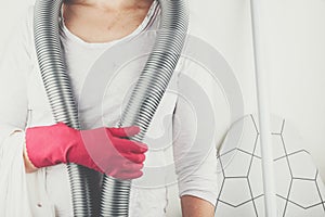 Person with red rubber glove and a vacuum cleaner around neck