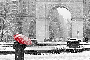 Person with red umbrella in black and white winter scene in New York City