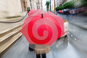 Person with red umbrella in the rainy city with zoom effect