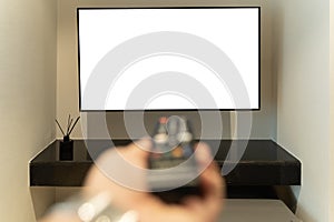 A person is relaxing on a sofa while holding a remote control in front of a flat-screen television