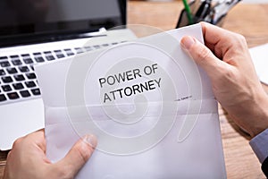 Person Removing Power Of Attorney Document From Envelope