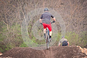 a person riding a dirt bike over a jump with another in the background