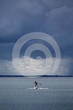 a person riding a surfboard on a body of water under dark clouds