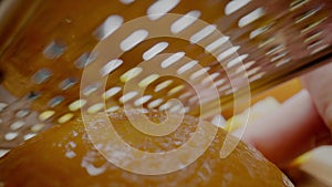 Person rubs juicy wet orange peel with metal grater macro