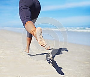 Person, running and feet at beach with exercise, sport and training for marathon by the sea. Workout, fitness and back