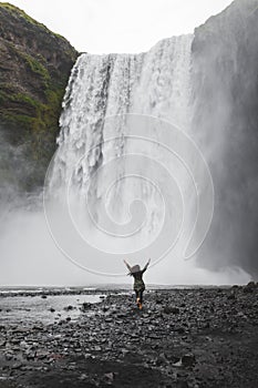 Person running to Skogafoss Iceland waterfall. Powerful stream, dramatic view