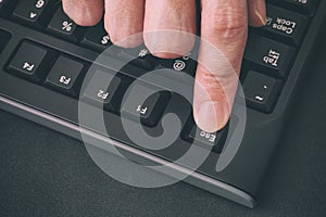 Person`s finger pressing Escape key on a black computer keyboard