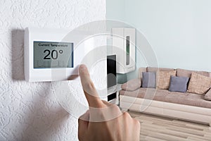 Person`s Hand Adjusting Digital Thermostat