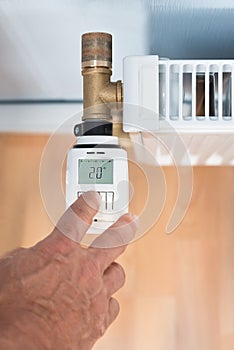 Person's hand adjusting temperature on thermostat