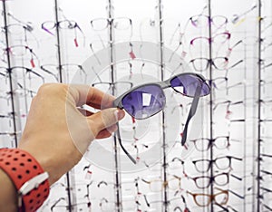 Person`s hand choosing a glasses sunglasses at the optics store