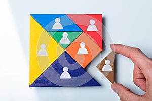 Person`s Hand Completing Tangram Puzzle