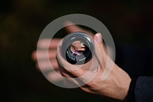Person's hand holding a 50 mm Minolta camera lens with focus on the inside of the lens