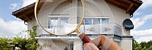 Person's Hand Holding Magnifying Glass Over Luxury House