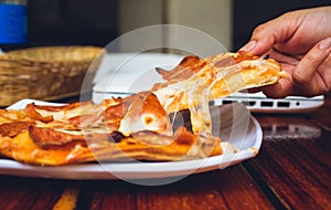 person's hand holding piece of pizza in restaurant photo