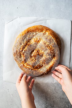 Person`s hand holding Ramadan pide with sesame seeds