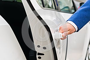 The person`s hand holds the handle of the car door and opens the car, close-up