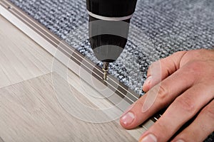 Person`s Hand Installing Carpet On Floor