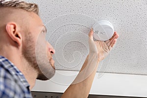 Person`s Hand Installing Smoke Detector On Ceiling