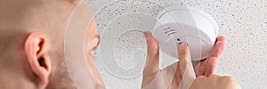 Person's Hand Installing Smoke Detector On Ceiling