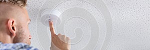 Person's Hand Installing Smoke Detector On Ceiling