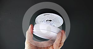 Person's Hand Installing Smoke Detector On Ceiling Wall