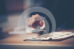 A Person`s Hand Stamping With Approved Stamp On Document At Desk