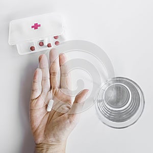 person s hand taking tablet from pill organizer box white background. High quality photo