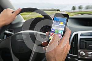 Person's hand using cellphone while driving a car