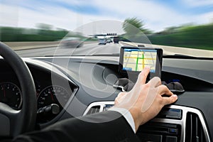 Person's hand using gps navigation system in car