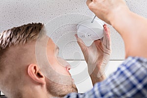 Person`s Hand Using Screwdriver To Install Smoke Detector