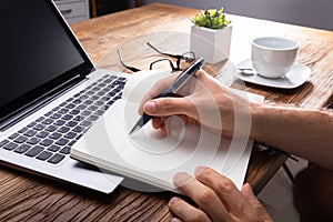 Person`s Hand Writing On Black Notebook