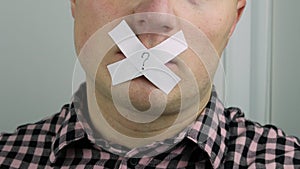 A person`s mouth is closed with adhesive tape, lips are sealed with sticky tape, a plaster on the lips.