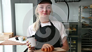 Person saleswoman keeping smile on face. Female baker giving coffee croissant