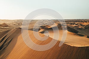 Person on sand dune in desert sunset of Huacachina, Ica, Peru, South America