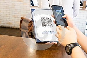 Person scanning contactless menu QR code with smartphone as new normal. Dummy code used